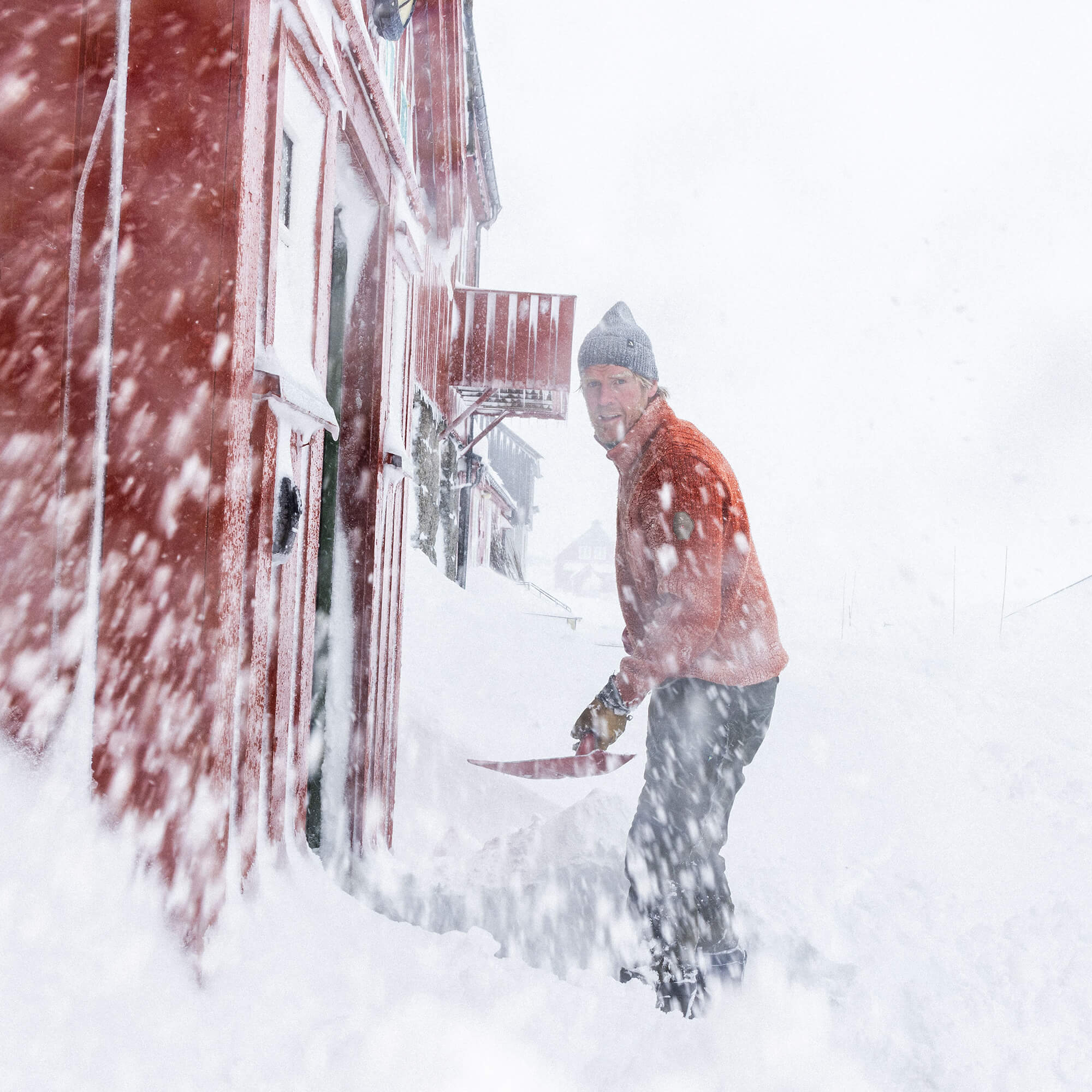 Mann på snøfjell med Janus Wool Finse genser i farge rød