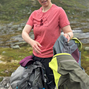 Person in Janus merino pink shirt with hiking gear in a mountainous area