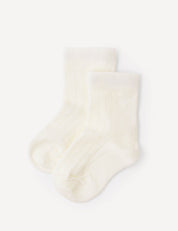A pair of Socks – Merino Baby Light in the Marshmallow color, featuring a soft, ribbed texture, is laid flat on a white background. These breathable merino baby socks provide gentle comfort for little feet.