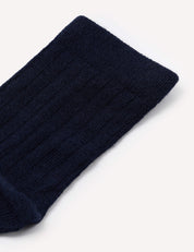 Close-up of the upper section of a navy blue, ribbed Daily Socks – Merino Kids sock against a plain white background.
