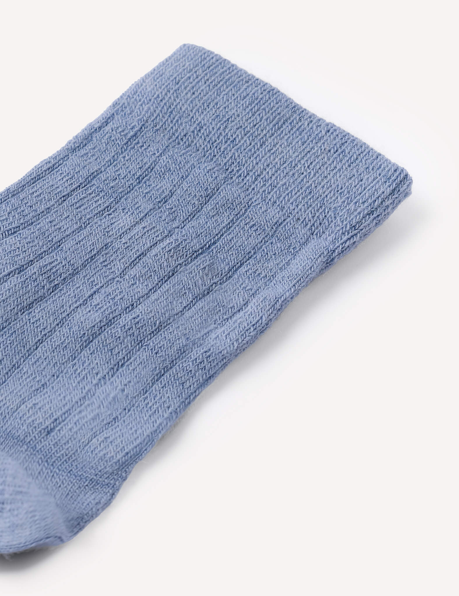 A close-up of a single light blue Daily Socks – Merino Kids thin wool sock with a ribbed knit texture, displayed on a plain white background.