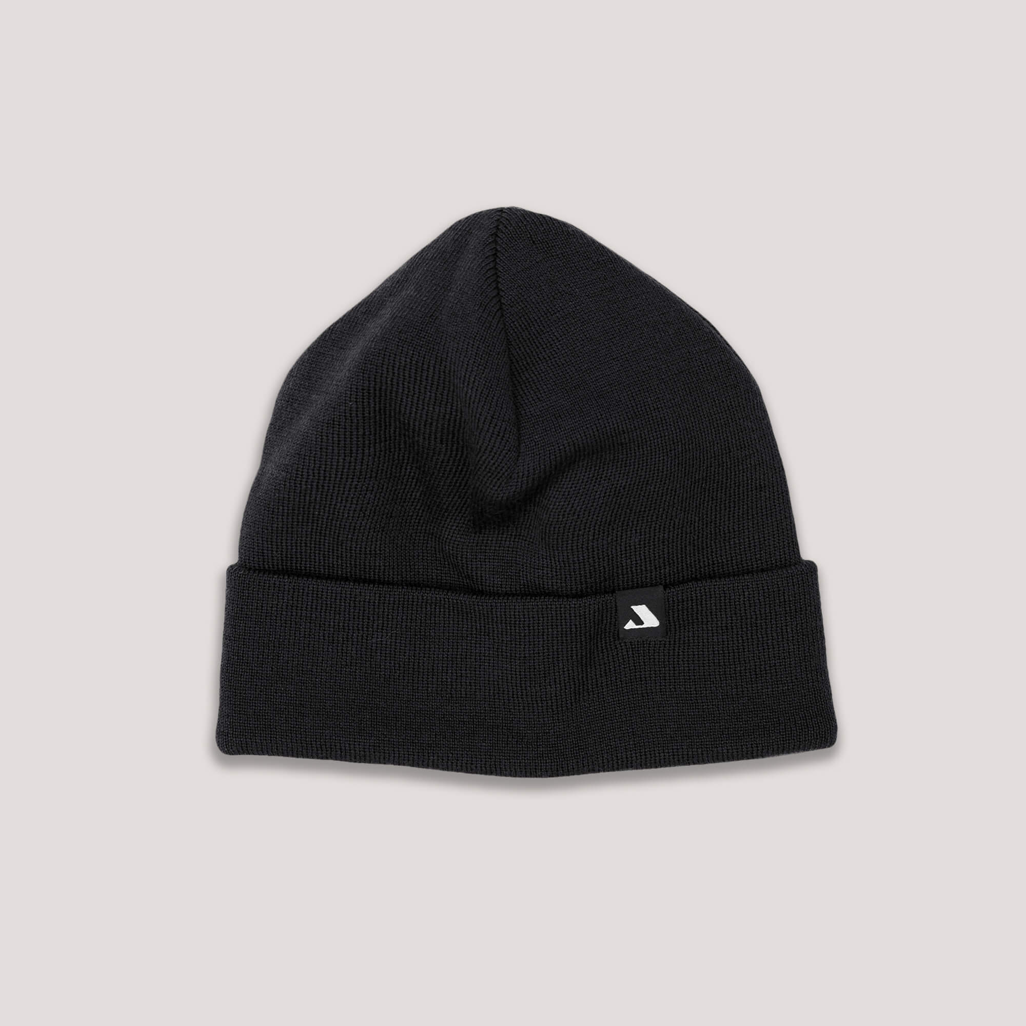 The Beanie – MeshWool in black is a merino wool beanie with a folded cuff and a small front tag featuring a white logo, shown on a light grey background.