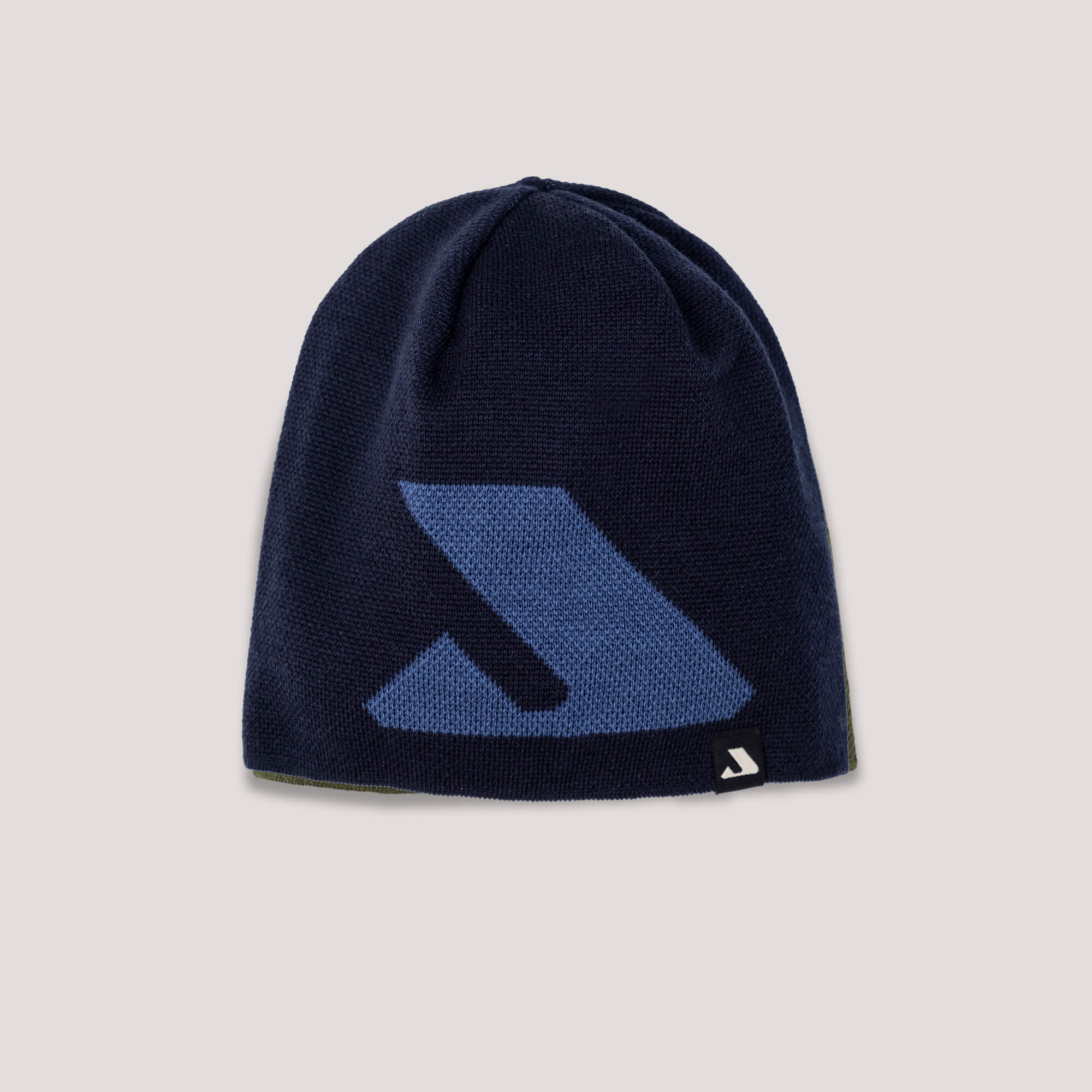 The Beanie – Logo is a navy merino wool hat featuring a large blue geometric logo and a small black-and-white tag, designed for warmth and breathability, shown on a light gray background.