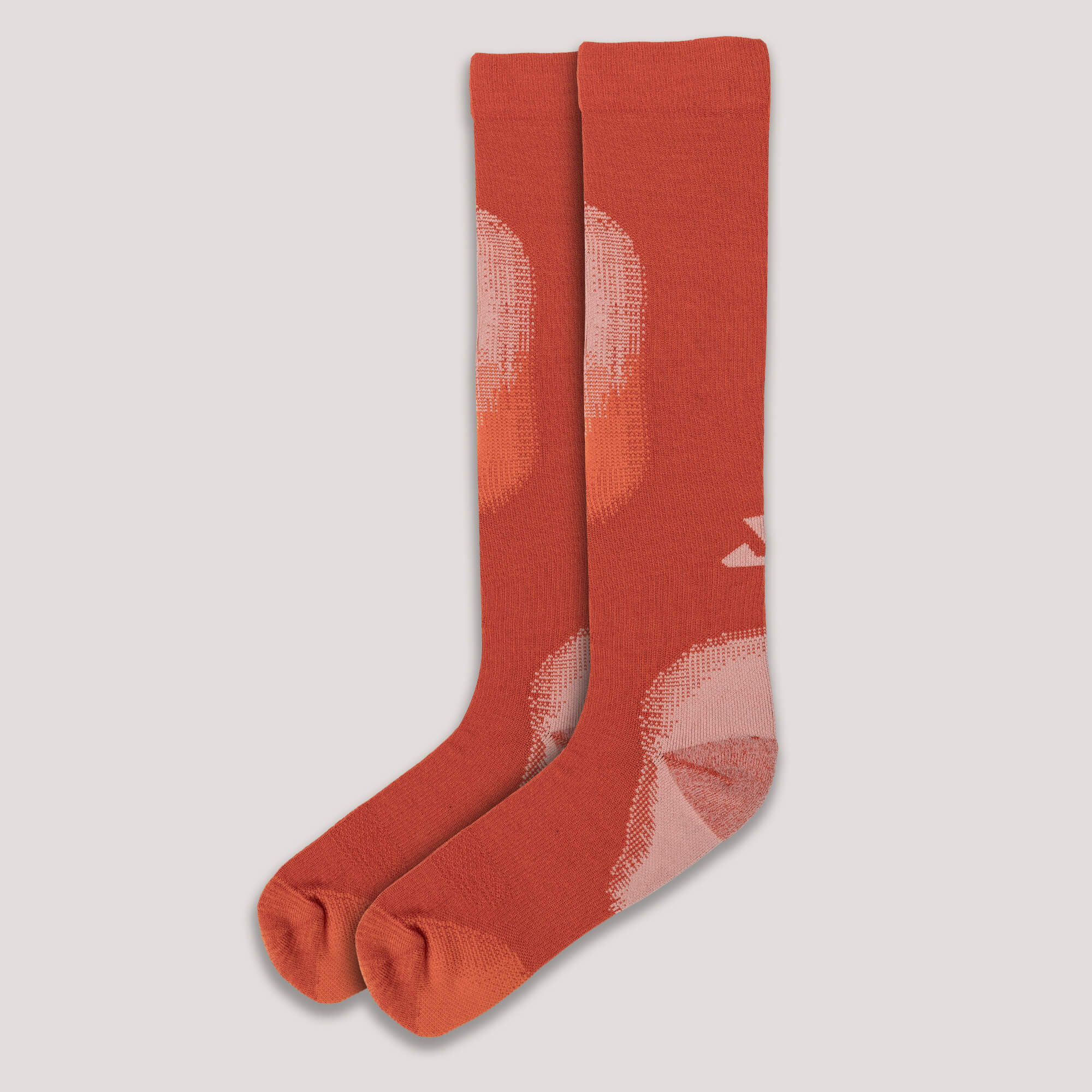 Pair of orange Janus Wool alpine ski socks with a lighter pattern on a light gray background