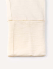 A close-up of a folded, cream-colored Merino Baby Light pyjamas fabric with a visible seam, possibly showing the cuff of a long sleeve top or pants, made from breathable material and displayed against a plain white background.