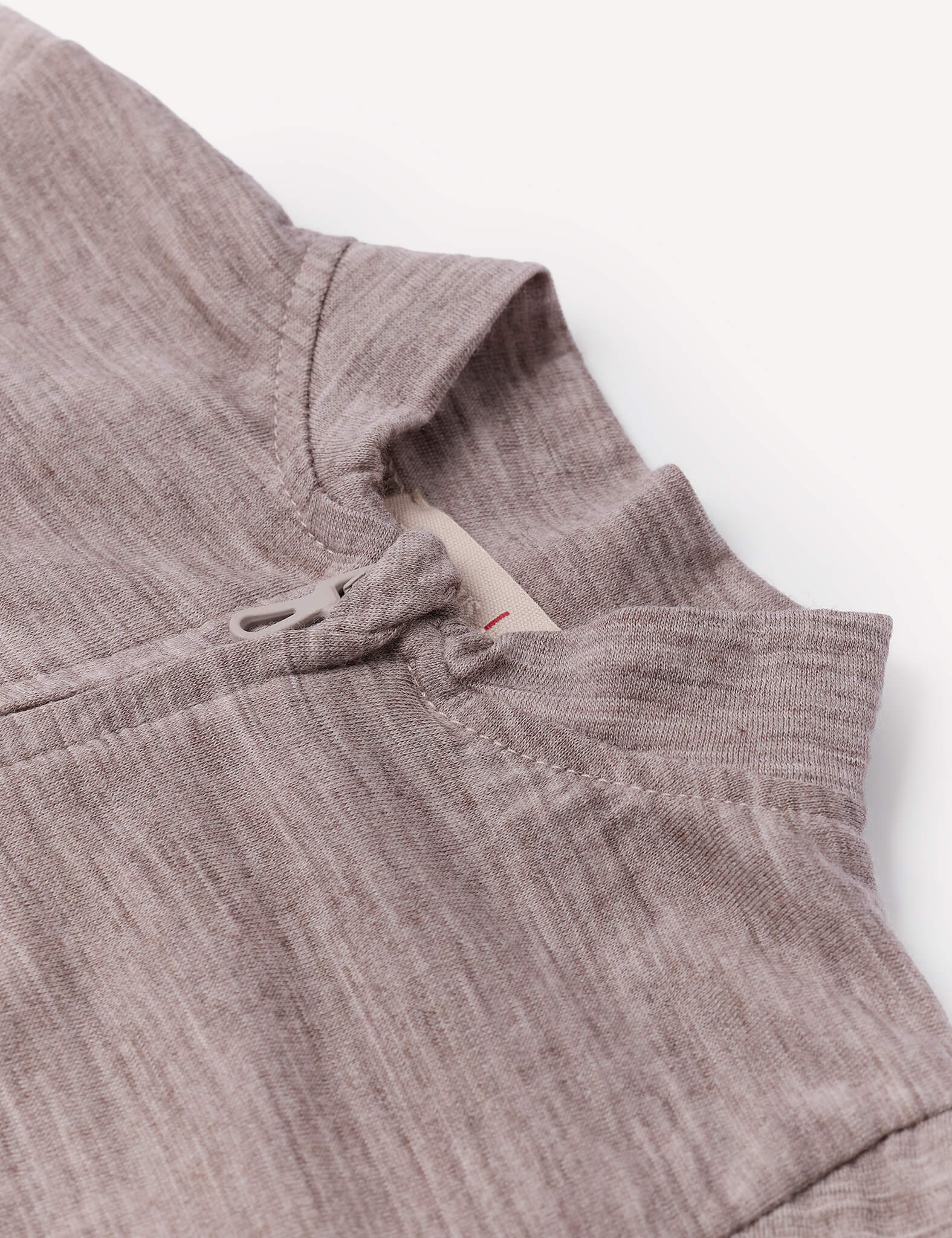 Close-up of the Pyjamas – Merino Baby Light in light brown, highlighting the collar, part of the shoulder seam, and a small fabric loop near the neckline against a plain white background—an ideal example of breathable sleepwear.