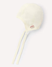 A lightweight Marshmallow-colored Bonnet – Merino Baby Light is displayed against a light background. Made from soft merino wool, this bonnet features long ties and a small red and white tag, offering a breathable and comfortable option for your baby.