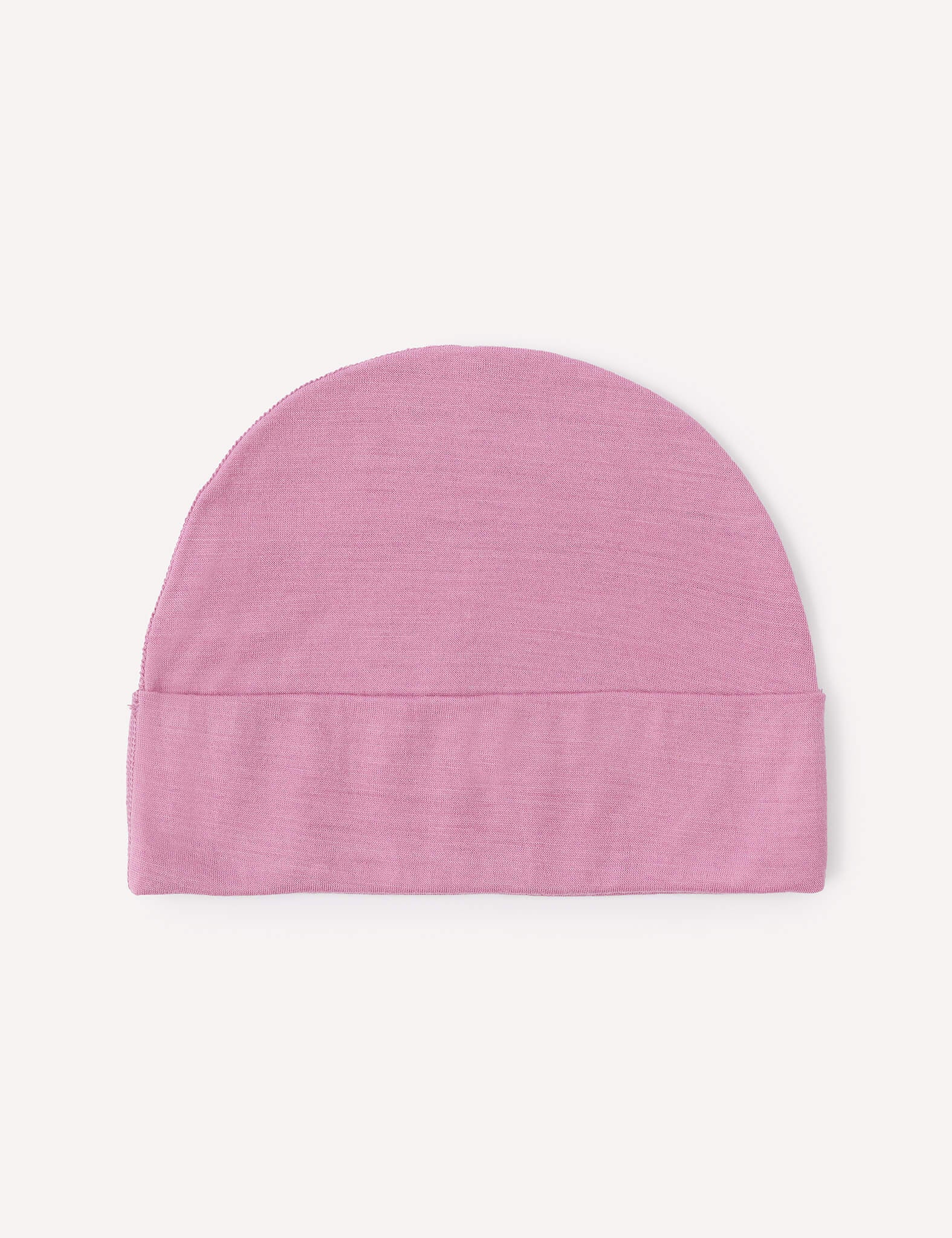 A lightweight Merino Baby Light Beanie in light pink, featuring a simple design with a folded brim, is laid flat on a plain white background.
