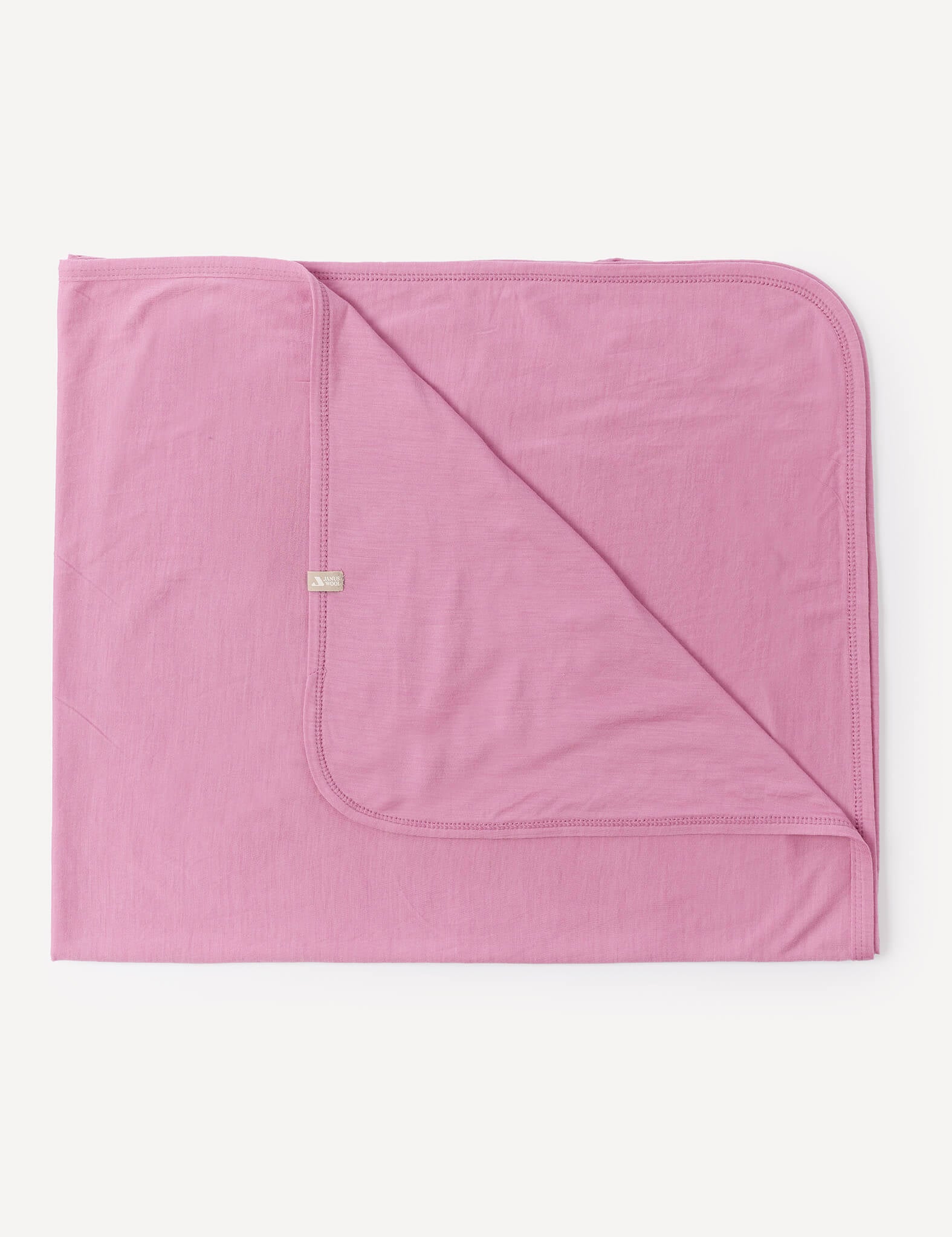 A neatly folded Blanket – Merino Baby Light in Mauve Orchid, featuring lightweight fabric, rounded corners, and visible stitching, displayed on a white background.