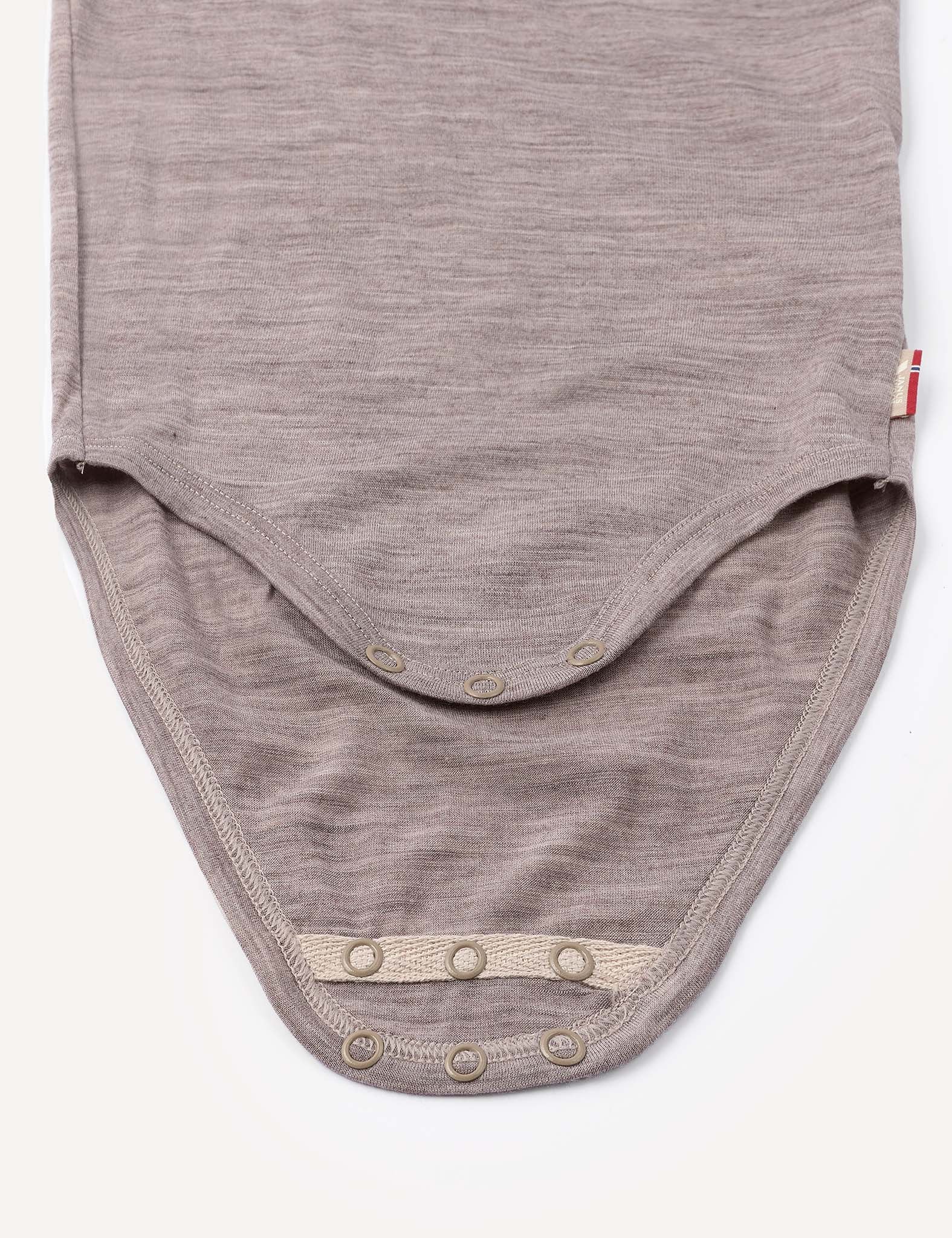 A close-up of the Body – Merino Baby Light in beige, highlighting the bottom snap buttons for easy diaper changes, laid flat on a white background.