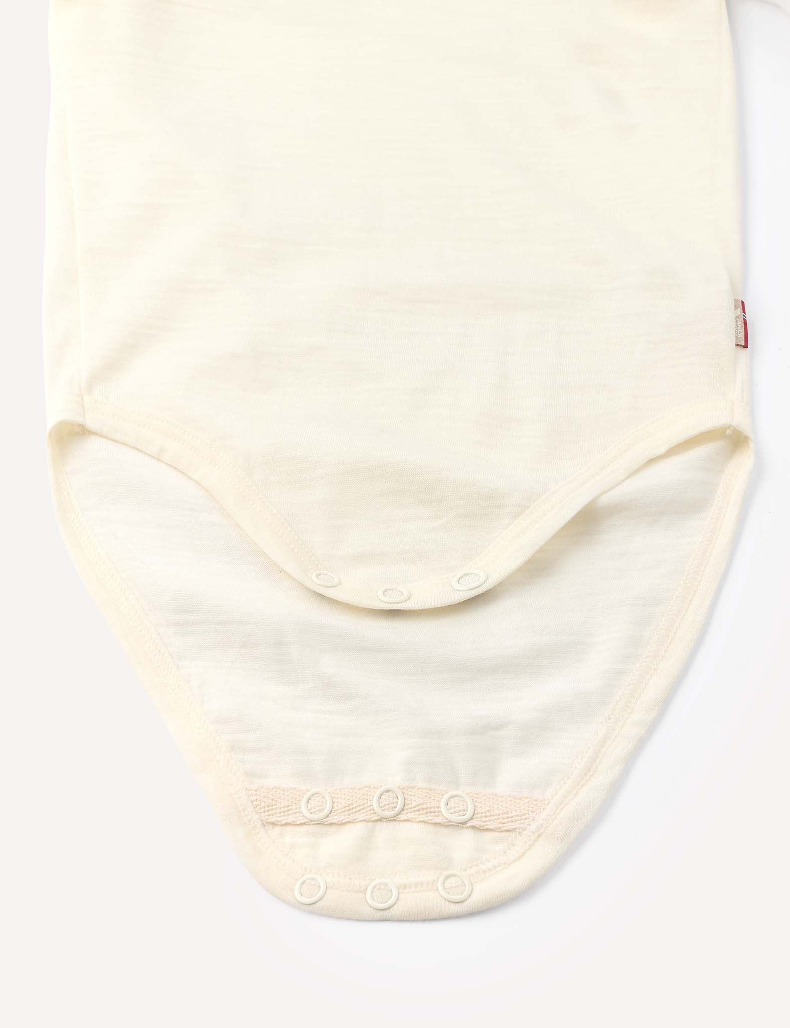 Close-up of the Body – Merino Baby Light, a cream-colored merino wool bodysuit featuring snap buttons at the bottom for easy fastening, laid flat on a light background.