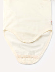 Close-up of the Body – Merino Baby Light, a cream-colored merino wool bodysuit featuring snap buttons at the bottom for easy fastening, laid flat on a light background.