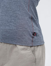 A close-up of a person in the T-shirt Active – Classic Merino 160 Women in heathered gray with a small black tag, paired with beige pants, showcasing the side seam and part of the shirt's hem.