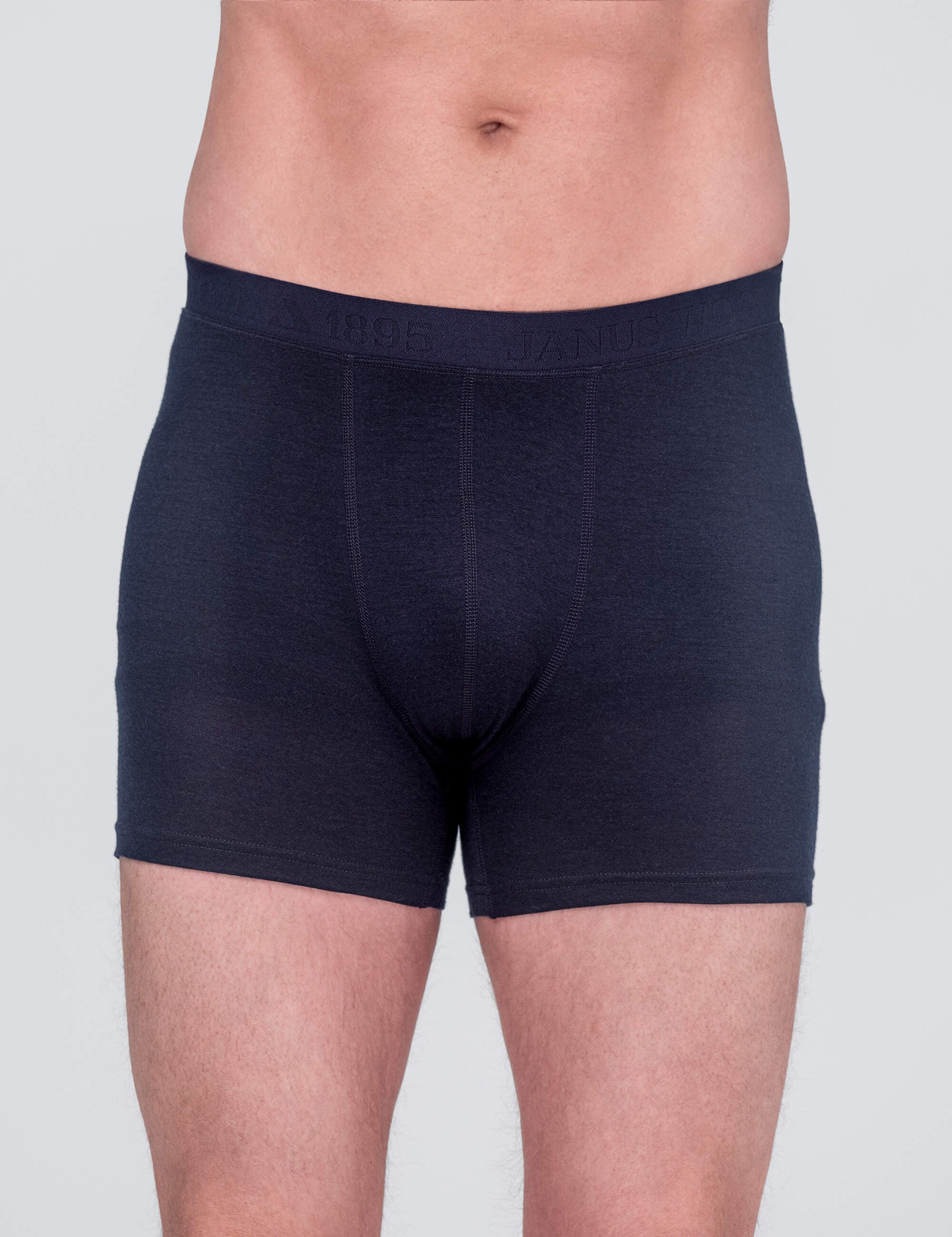 A person is shown from waist to mid-thigh wearing Boxers – Classic Merino 160 Men in Navy, featuring temperature regulating merino wool, against a light gray background.
