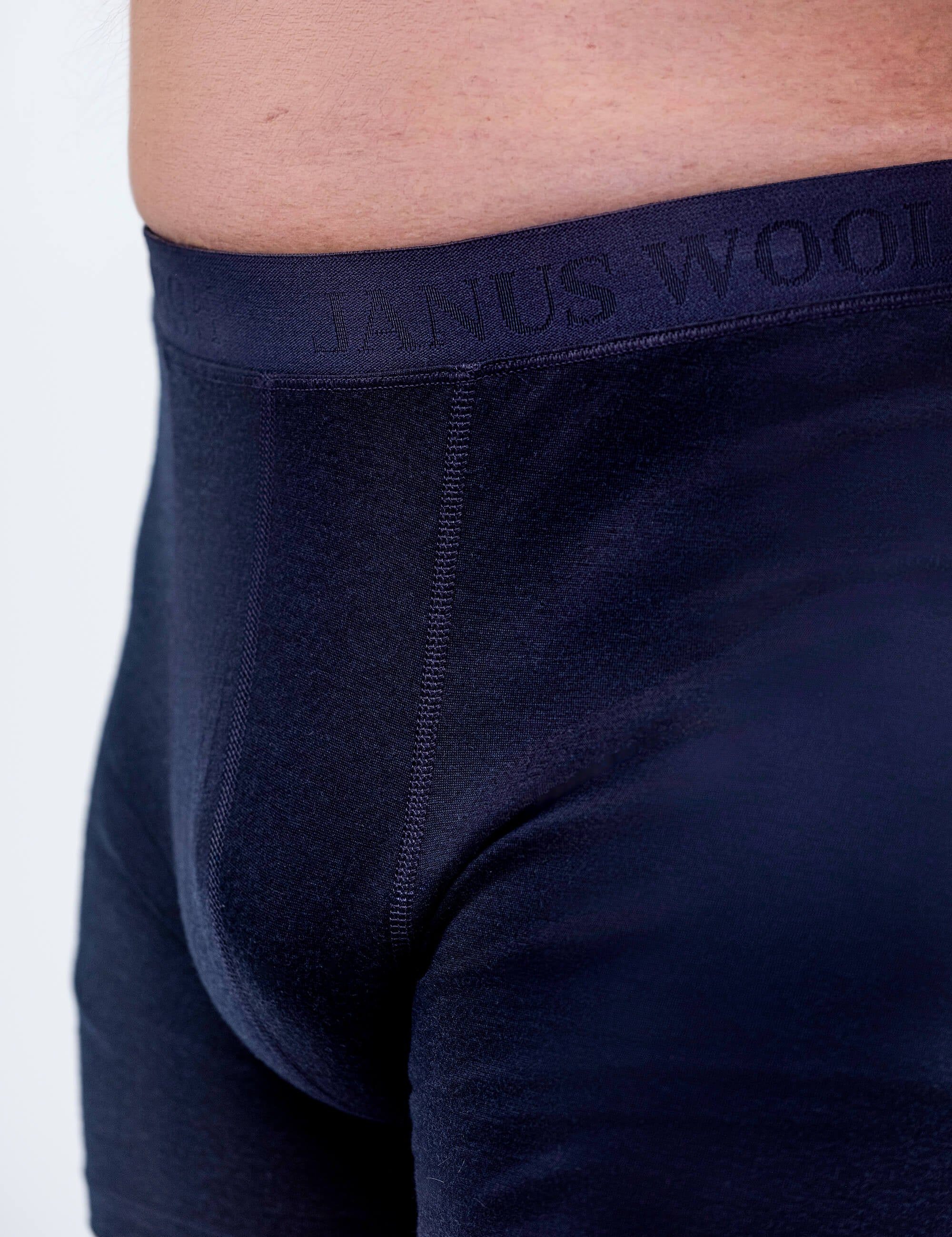Close-up of a person wearing Boxers – Classic Merino 160 Men in dark blue, showing the embossed waistband. The image highlights the waist and upper thigh, emphasizing comfortable, breathable, and temperature-regulating merino underwear.