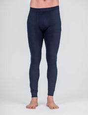 A person wearing navy Classic Merino 160 Men leggings, fitted and breathable, stands barefoot against a light gray background, shown from the waist down.