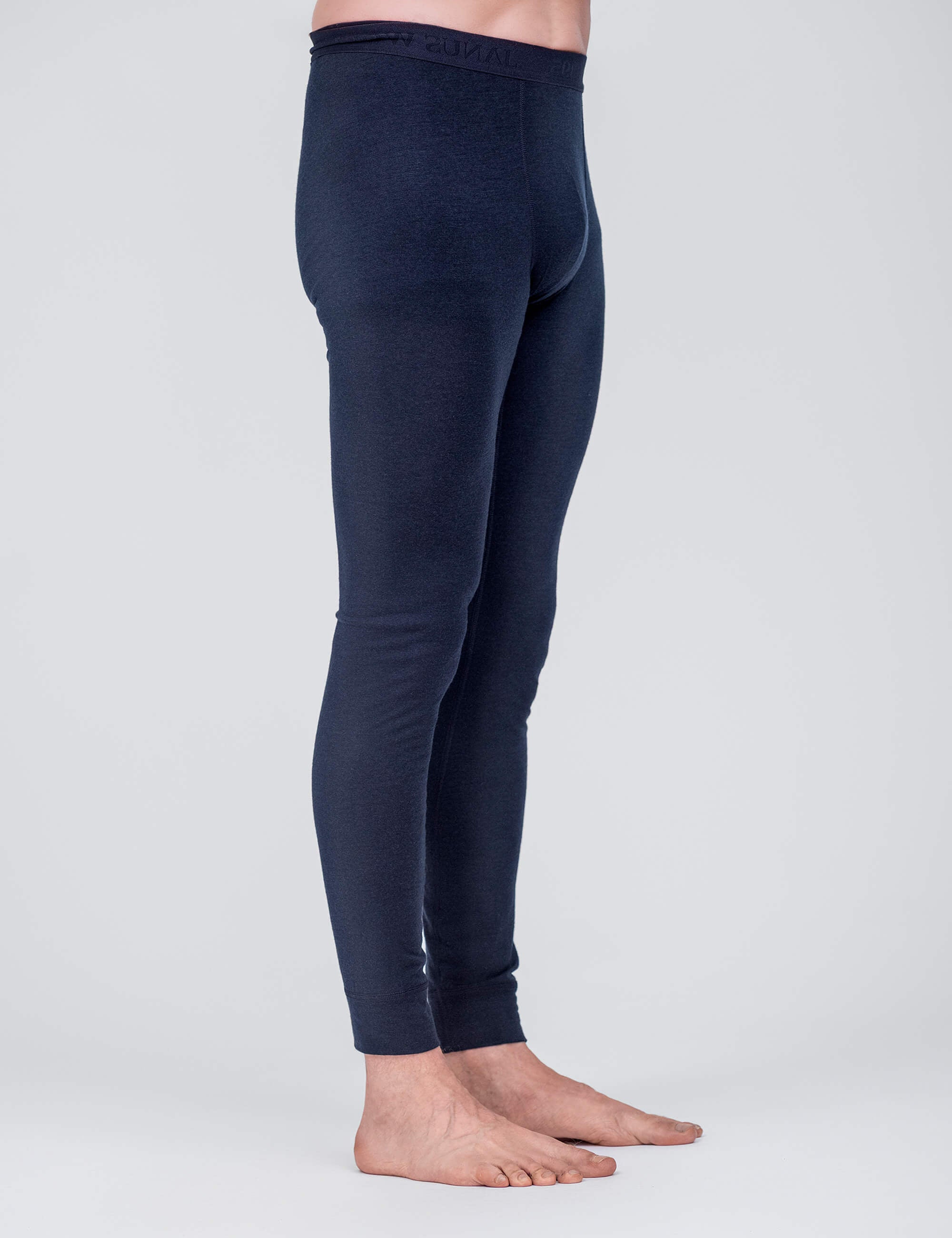 A person stands barefoot on a light gray surface, shown from the waist down in a side view, wearing dark blue, fitted Leggings – Classic Merino 160 Men known for their breathable and temperature regulating properties.