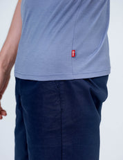 A person wearing the T-shirt Regular – Classic Merino 160 Men in light purple with a small red side tag and dark blue pants, shown from the waist down; their left arm is partially visible.
