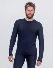 A man with short, tousled hair and a beard wears the Classic Merino 160 Men Crew Neck in Navy with matching pants, standing against a light gray background—an ideal choice for everyday wear.