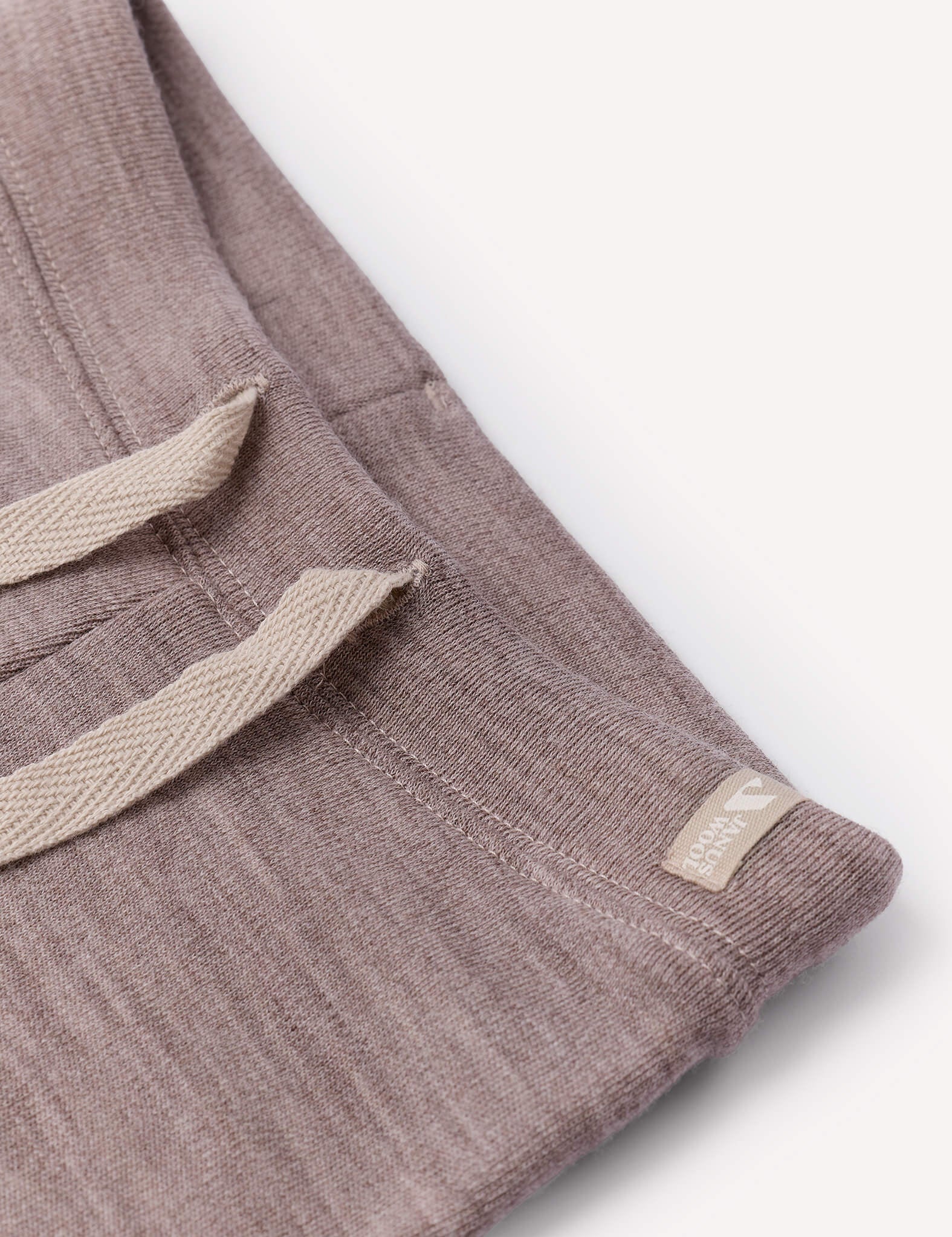 Close-up of brushed Pants – Merino Baby AirWool trousers featuring a beige adjustable drawcord and a small beige tag sewn near the seam, highlighting subtle stitch details and the soft texture against a white background.