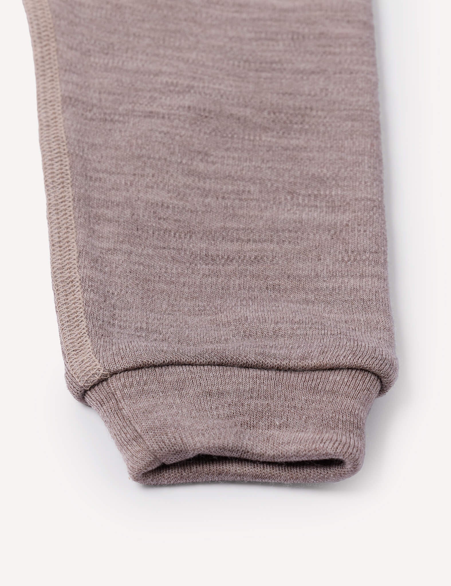 A close-up of the cuff of a light brown Merino Baby AirWool knit pant leg, highlighting the texture and stitching detail against a plain white background.