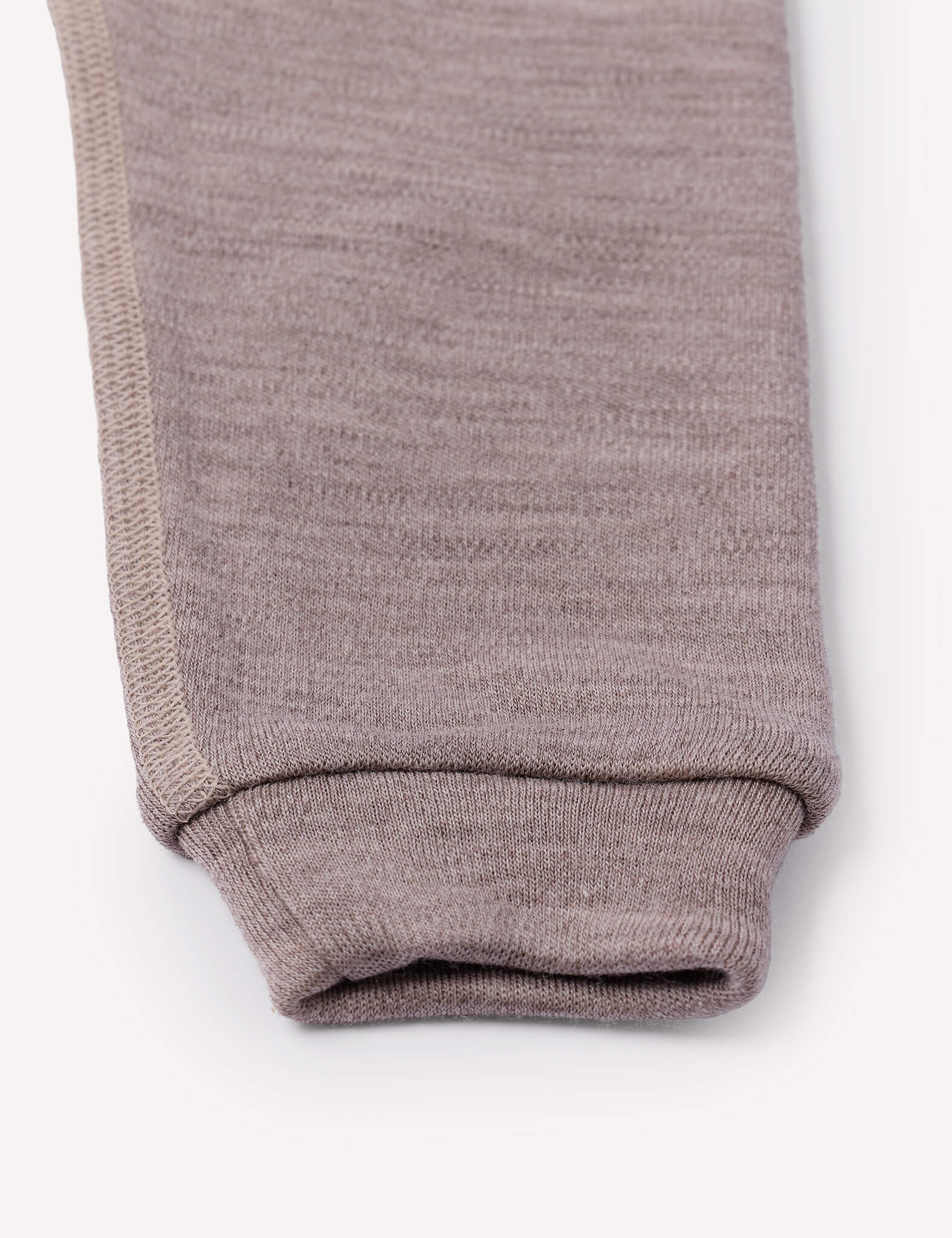 A close-up of the cuff of a light brown Merino Baby AirWool knit pant leg, highlighting the texture and stitching detail against a plain white background.