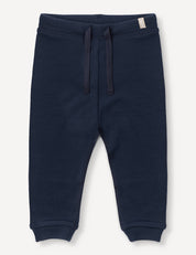 Navy blue Merino Baby AirWool pants featuring an adjustable drawcord waistband, ribbed cuffs, and a small tag on the waistband.