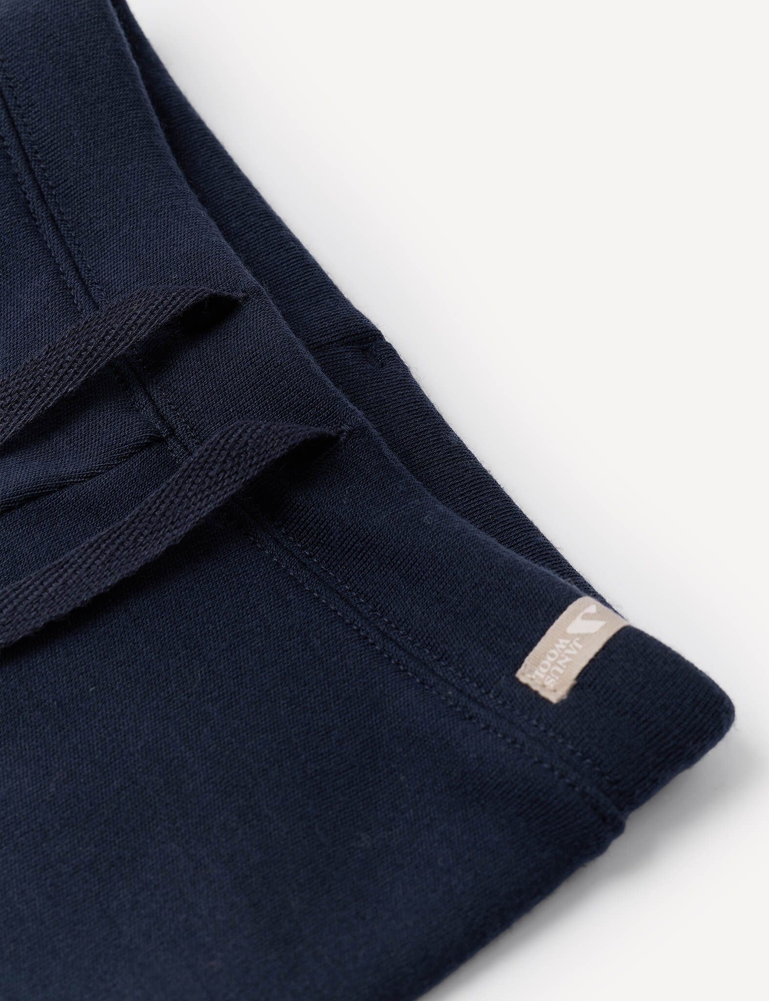 Close-up of the Pants – Merino Baby AirWool in navy blue, featuring an adjustable drawcord and a small beige tag on the seam, shown against a white background.