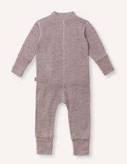The Onesie – Merino Baby AirWool in light brown is displayed flat with the back side facing up. This long-sleeve baby onesie features a closed back seam, ribbed cuffs at the wrists and ankles, and a small red tag on the left side.