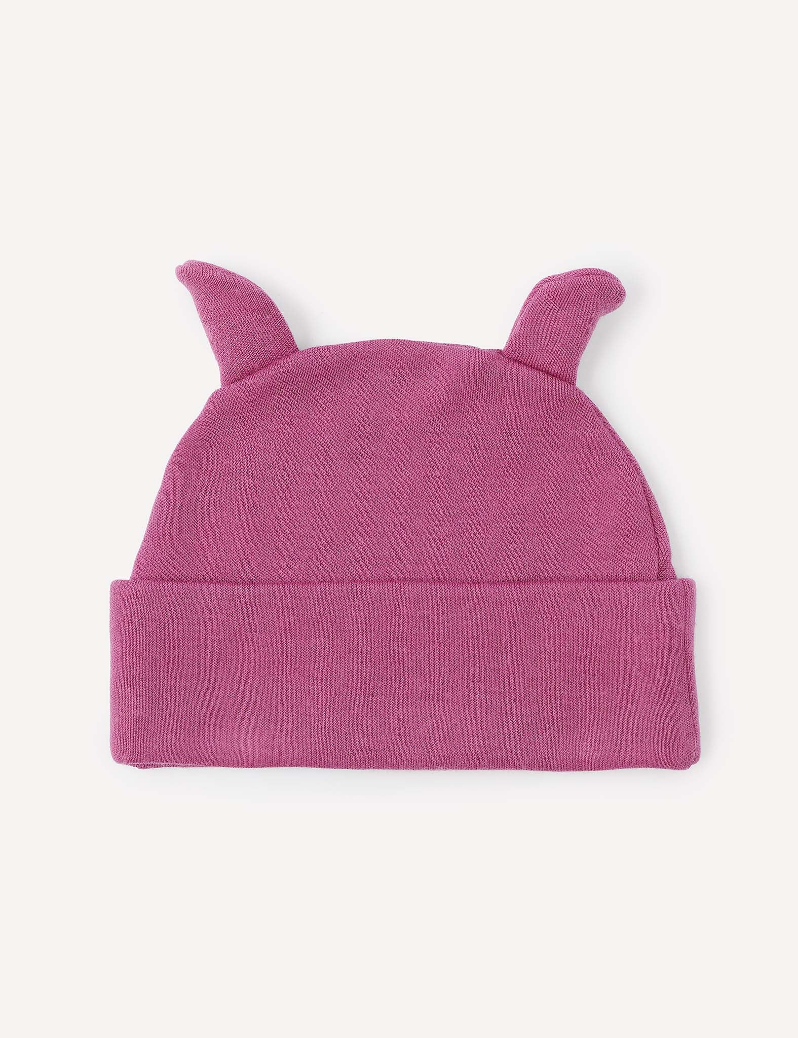 A Beanie – Merino Baby AirWool in pink, featuring two small pointed ear-like shapes on top, is laid flat on a light background. Crafted from merino wool, this baby beanie provides breathable insulation for comfort.