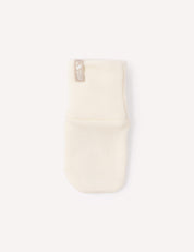 A single Mittens – Merino Baby AirWool in cream, crafted from soft merino wool with a beige tag, is displayed on a plain white background.