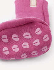 A close-up of the bottom of the Booties – Merino Baby AirWool in pink, featuring light pink non-slip grip patterns shaped like coffee beans or split circles, resembling warm baby booties.