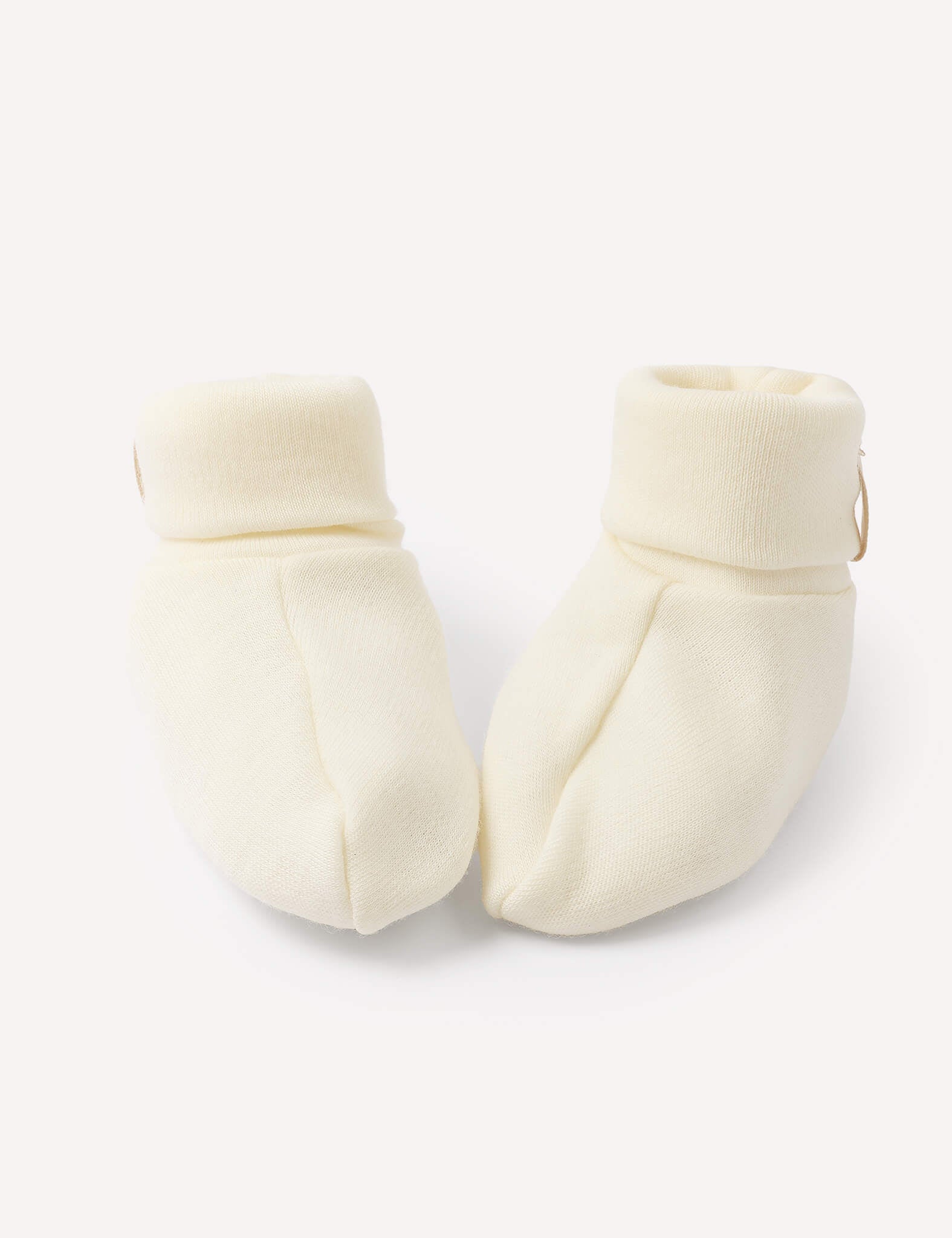 A pair of Booties – Merino Baby AirWool in Marshmallow, crafted from soft knit merino wool with folded cuffs, placed side by side on a plain white background.