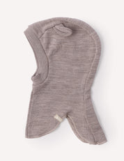 The Balaclava – Merino Baby AirWool is a soft, light brown merino wool headwear with a rounded hood and flared edges, designed for breathability and shown laid flat against a plain white background.