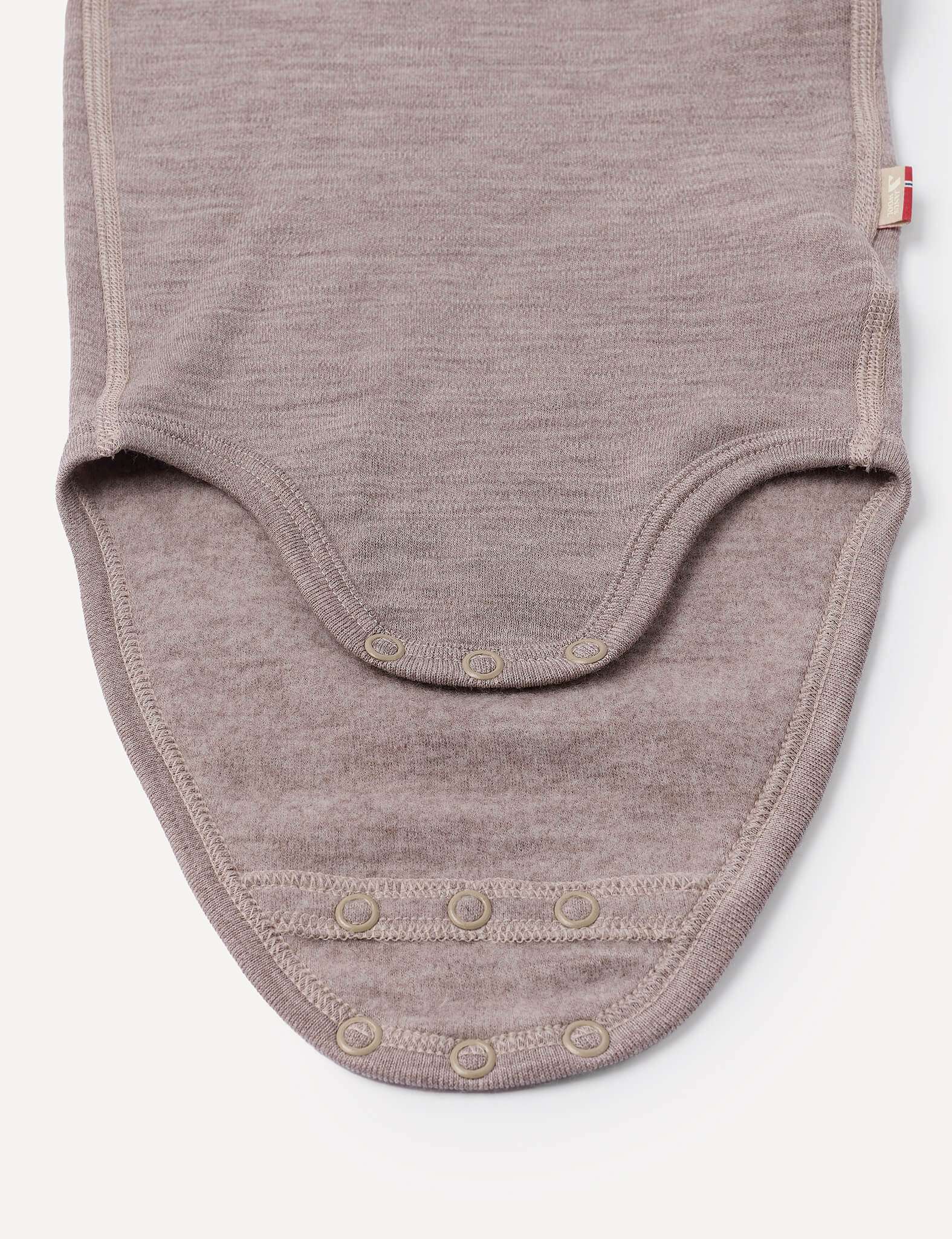 A close-up of the Body – Merino Baby AirWool in beige, crafted from soft merino wool fabric, highlights the bottom section featuring three snap buttons for easy closure and breathable comfort during diaper changes.