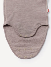 A close-up of the Body – Merino Baby AirWool in beige, crafted from soft merino wool fabric, highlights the bottom section featuring three snap buttons for easy closure and breathable comfort during diaper changes.