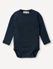 The Body – Merino Baby AirWool in navy is a long-sleeve merino wool bodysuit featuring snap buttons at the bottom for easy changing and offering breathable insulation, shown against a white background.
