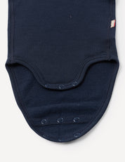 Close-up of the Body – Merino Baby AirWool in navy blue, featuring three snap buttons along its curved bottom edge, displayed against a plain white background.