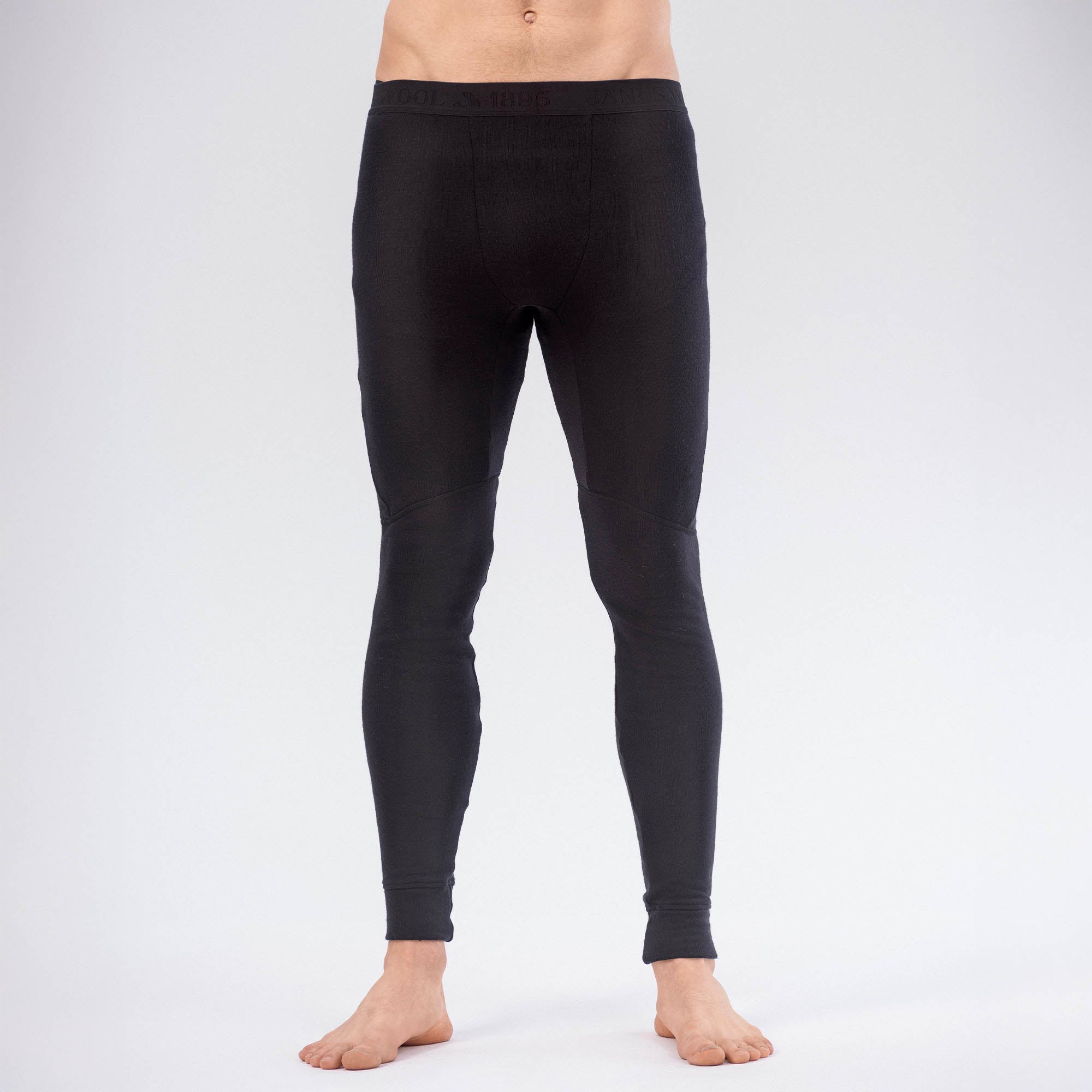 A barefoot person wears Leggings Merino – AirWool 260 Men, shown from waist down against a plain light background. The image highlights the warmth and breathability of the merino wool fabric.
