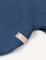 Close-up of a blue ribbed fabric from the Balaclava – Merino Kids AirWool collection, featuring a beige tag. The edge of this warm balaclava is shown with visible stitching detail against a white background.
