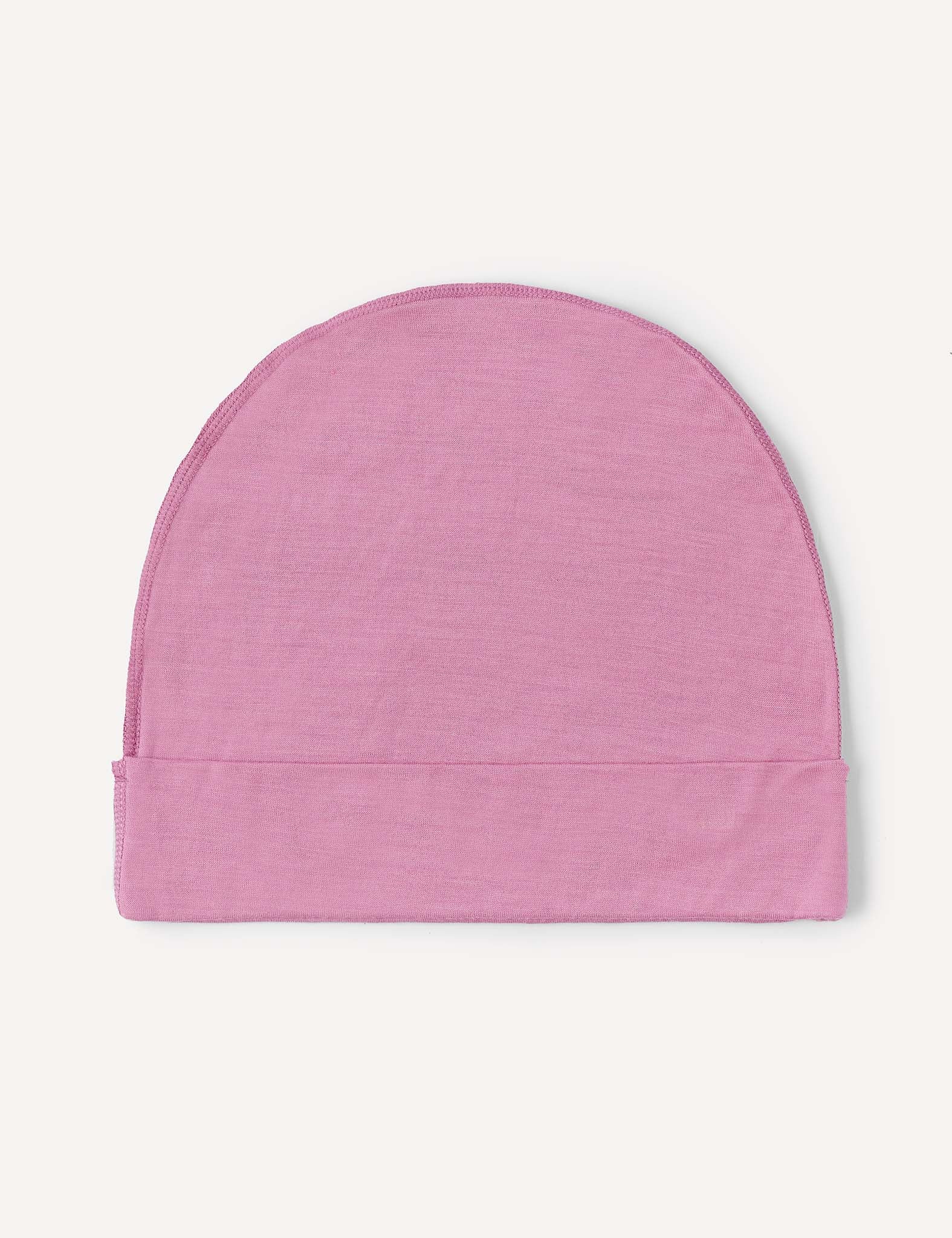The Beanie – Merino Kids Light in a soft, light pink wool is laid flat on a white background.