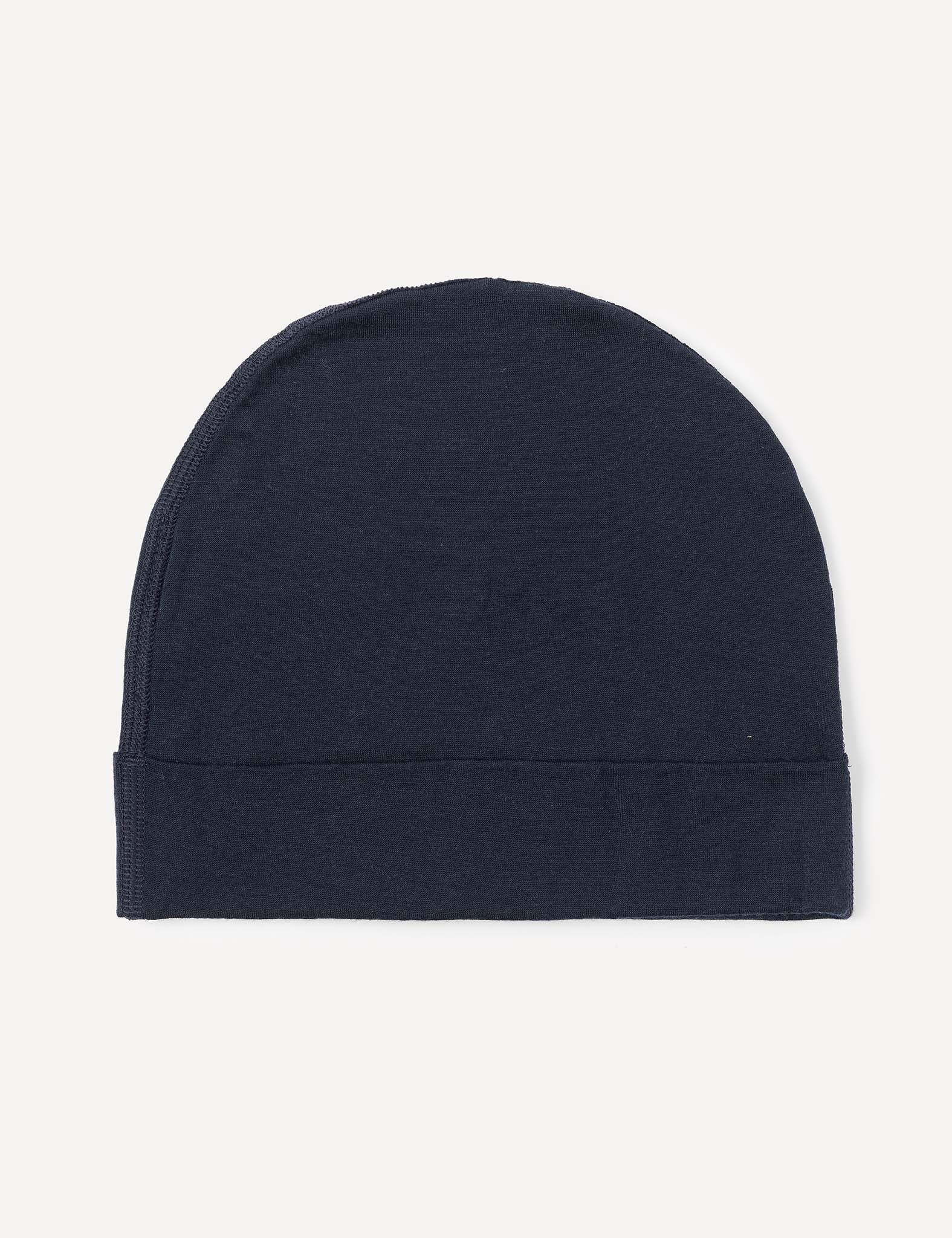 The Beanie – Merino Kids Light, crafted from soft wool in a plain, dark navy blue shade, is displayed flat against a light background. This beanie features a minimalist, seamless design with a folded edge at the bottom.
