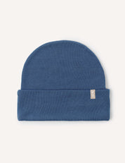 An Ensign Blue Beanie – Merino Kids AirWool is laid flat on a light background. The beanie features a folded brim with a small beige tag sewn near the right side, providing extra warmth and breathable comfort.
