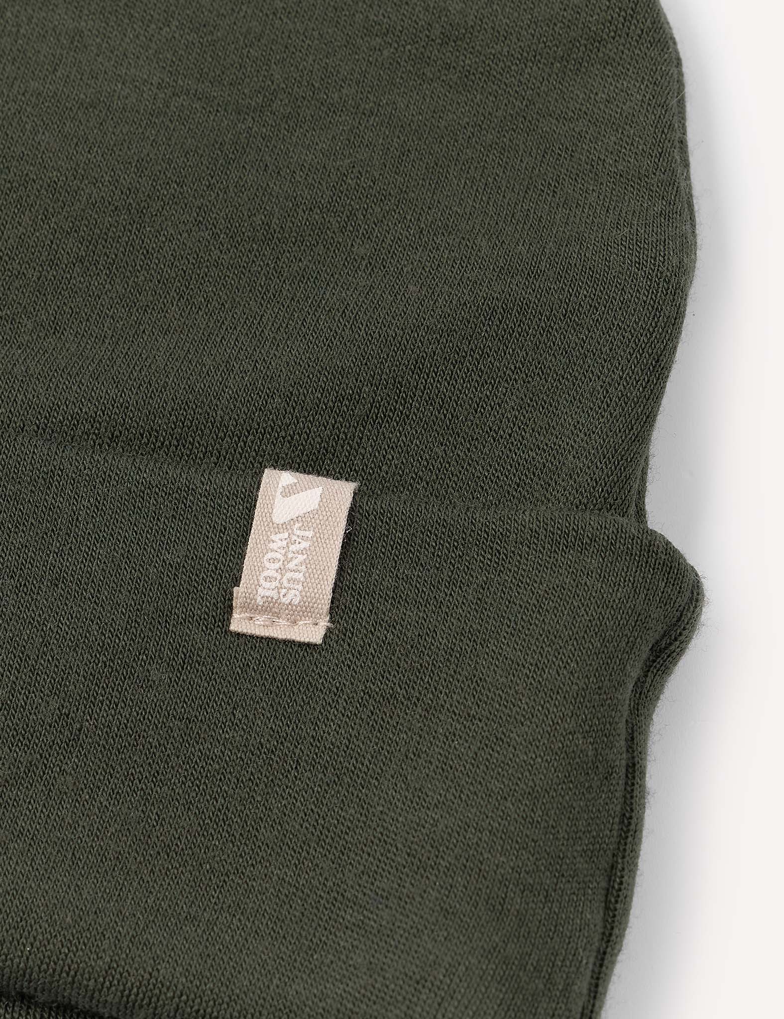 A close-up view of the Beanie – Merino Kids AirWool in dark green, featuring a small beige tag.