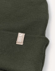 A close-up view of the Beanie – Merino Kids AirWool in dark green, featuring a small beige tag.
