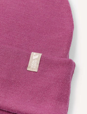 A close-up of the Beanie – Merino Kids AirWool in purple, featuring a small white fabric tag. This extra warm and breathable accessory is perfect for keeping kids comfortable on chilly days.