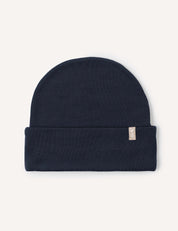 The Beanie – Merino Kids AirWool in Navy is folded flat with a small beige tag on the cuff, displayed on a light background. Made from breathable merino wool, this beanie provides extra warmth for chilly days.