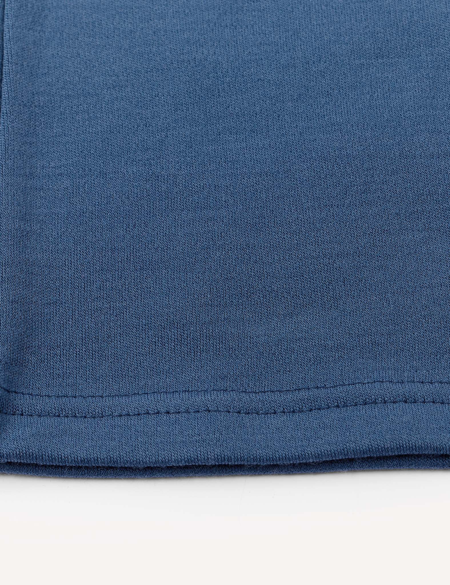 Close-up of the hem of a Flarepants – Merino Kids AirWool in blue, highlighting the stitching detail and soft texture against a white background.
