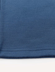 Close-up of the hem of a Flarepants – Merino Kids AirWool in blue, highlighting the stitching detail and soft texture against a white background.