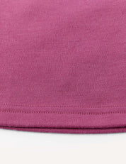 Close-up of the hem and fabric texture of a mauve or pinkish-purple Flarepants – Merino Kids AirWool garment, made from warm, comfortable brushed AirWool 260, against a white background.